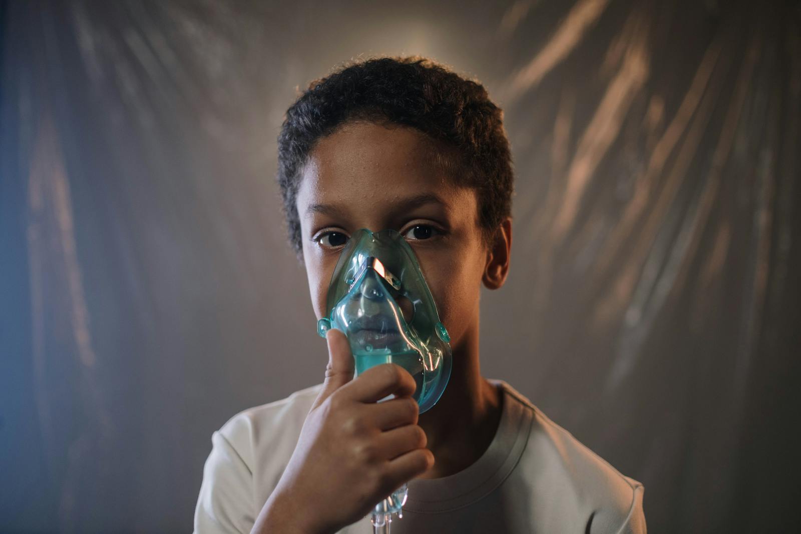 Portrait of a child using an oxygen mask indoors, highlighting health care needs.