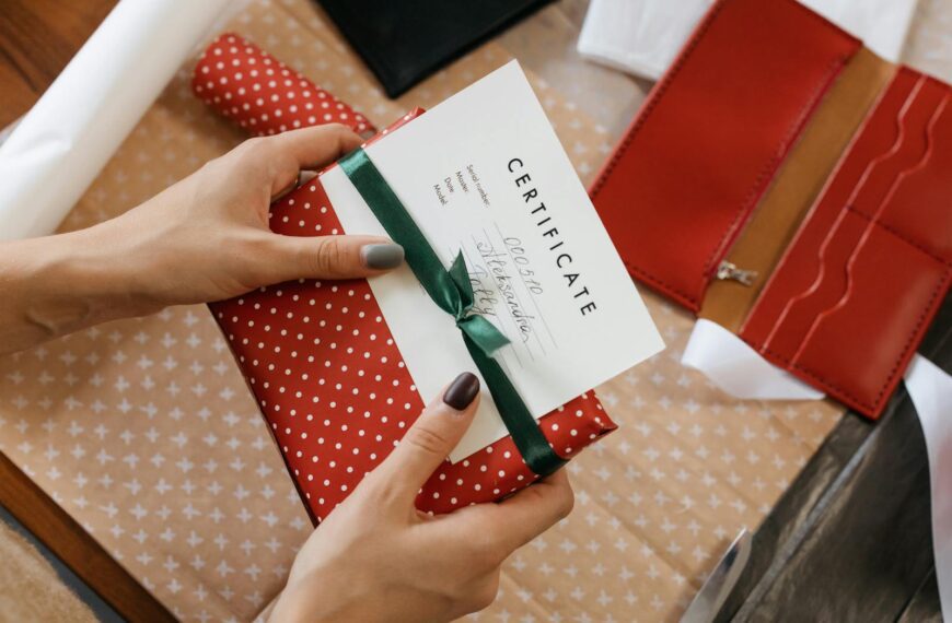 Close-up of hands holding a gift certificate wrapped in red polka dot paper and green ribbon.