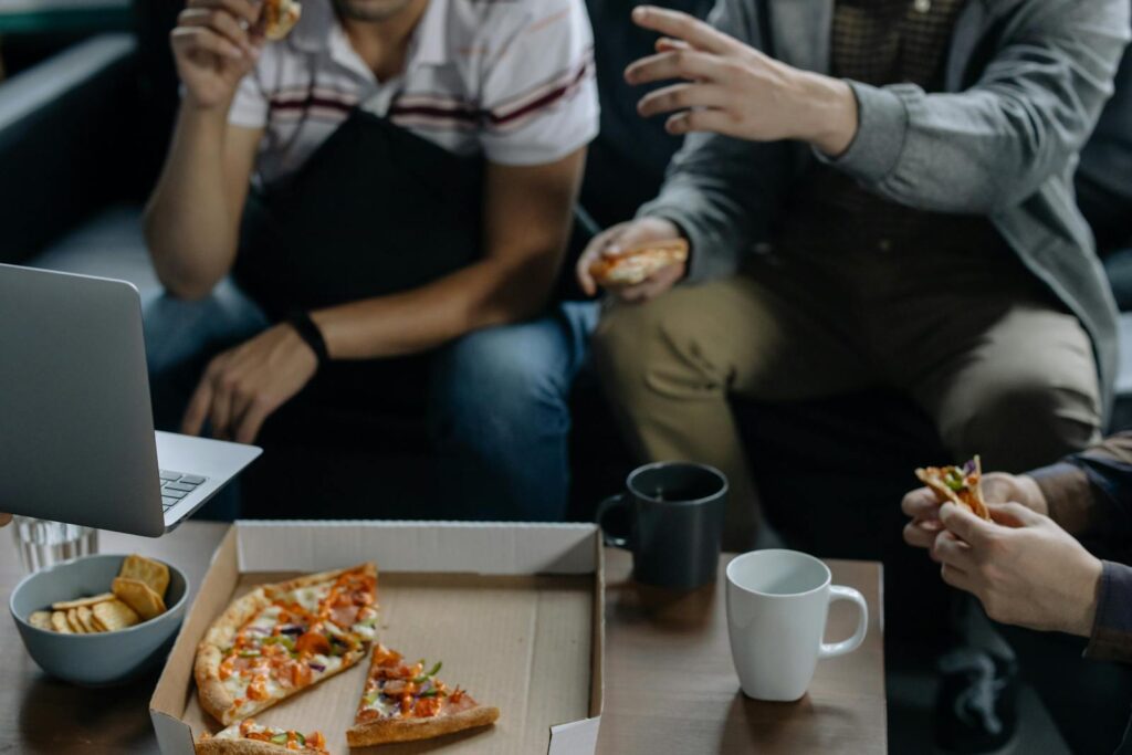 Friends enjoying pizza and snacks during a casual indoor gathering.