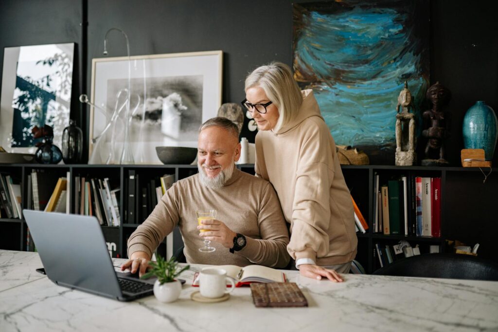 Elderly couple using a laptop at home, enjoying online activities and companionship.