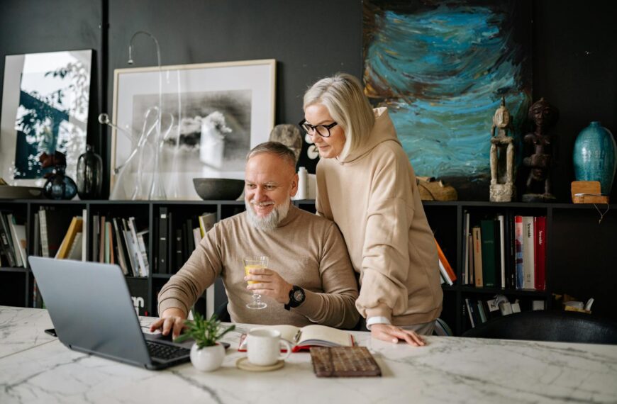 Elderly couple using a laptop at home, enjoying online activities and companionship.