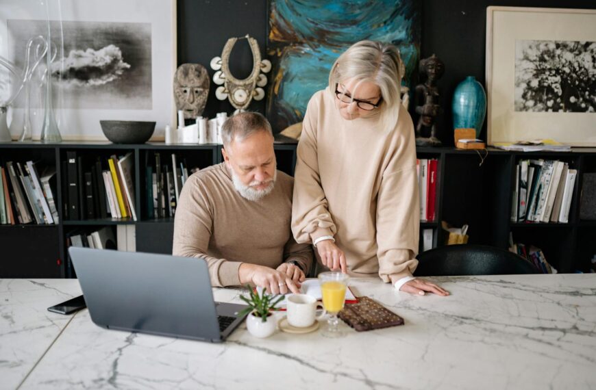 Elderly couple working together on a laptop in a cozy home office setting.