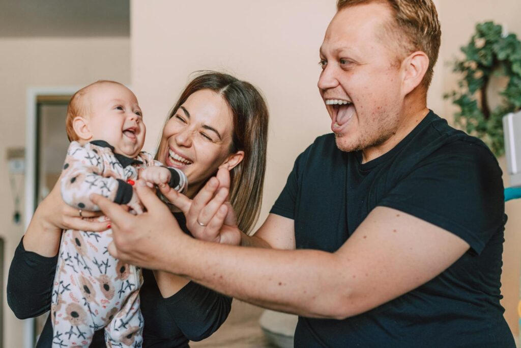 A happy family of three laughing and bonding indoors, showcasing love and warmth.