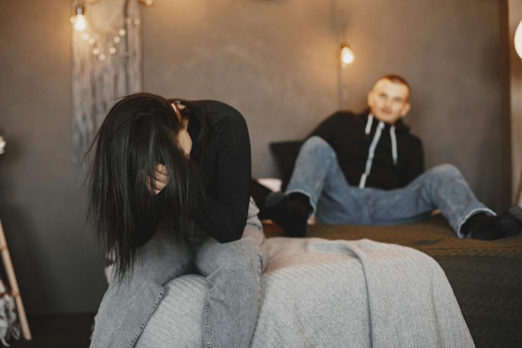 A couple having an intense conversation on a bed, reflecting relationship tension.