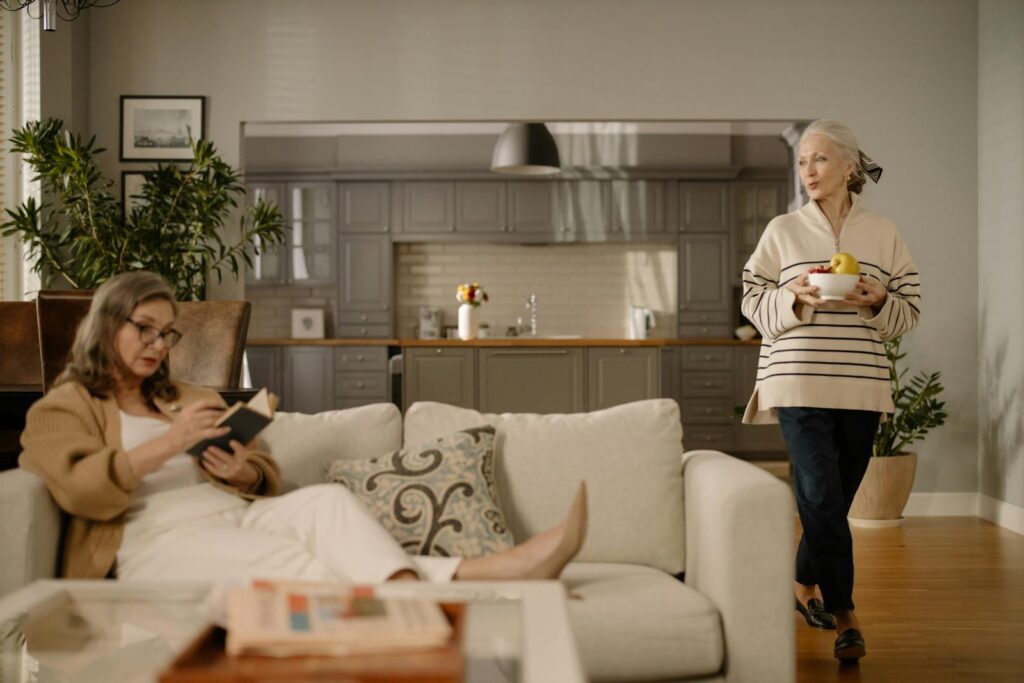 Women enjoying a cozy afternoon indoors, reading and relaxing on a sofa in a modern living room.