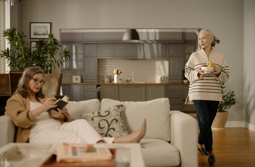 Women enjoying a cozy afternoon indoors, reading and relaxing on a sofa in a modern living room.
