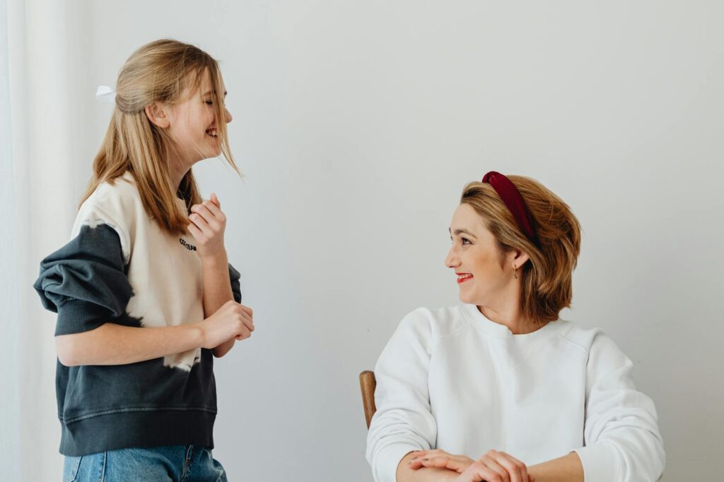 Mother and daughter sharing a joyful moment indoors with smiles and laughter.