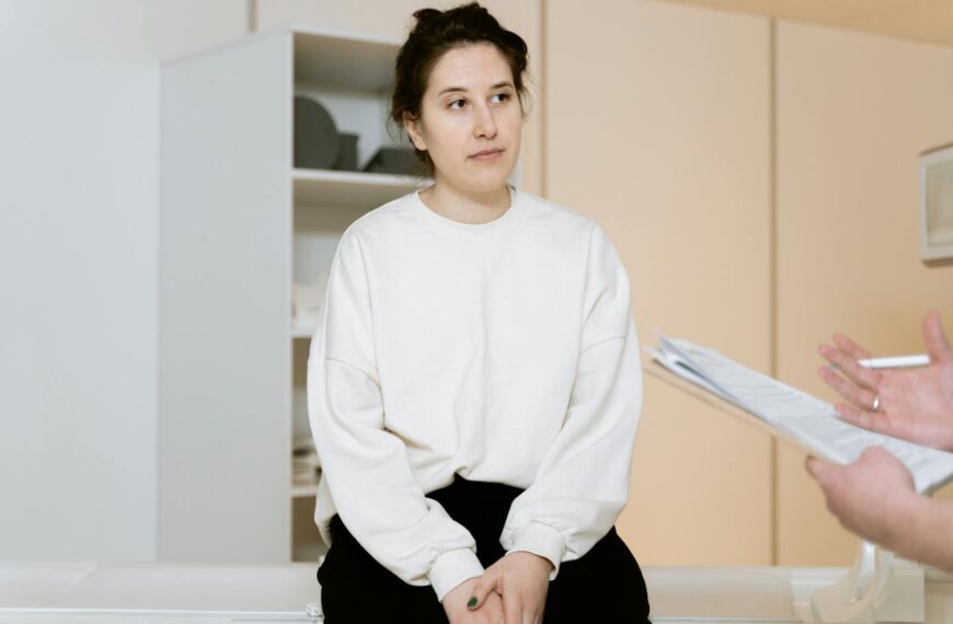 Adult woman sitting attentively during a medical consultation inside a clinic.
