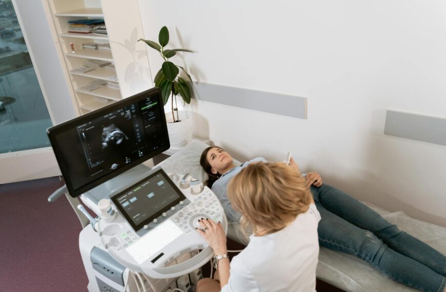 Pregnant woman receiving ultrasound consultation from medical professional in clinic.
