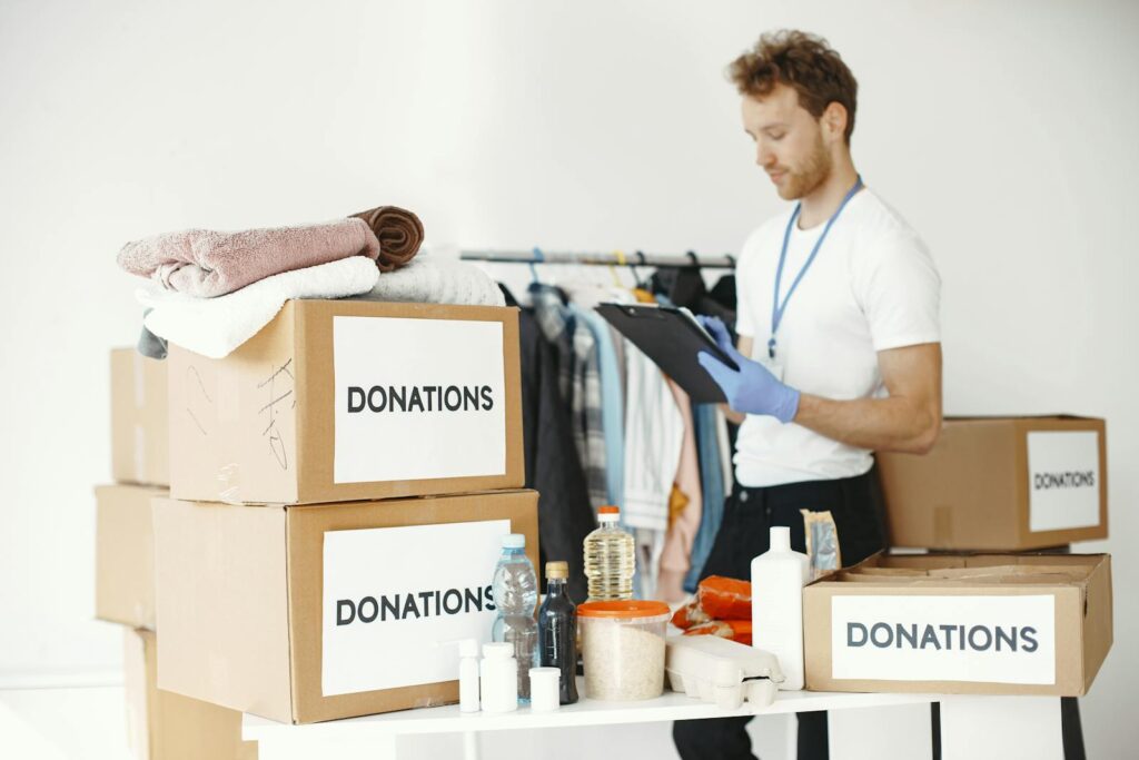Volunteer organizing various goods for donation. Charitable cause and community support.