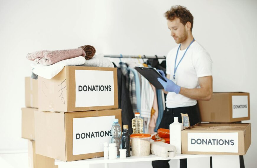 Volunteer organizing various goods for donation. Charitable cause and community support.
