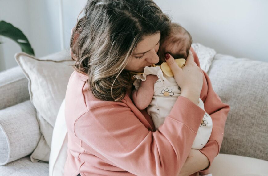 A mother lovingly embraces her baby at home, creating a warm and cozy atmosphere.