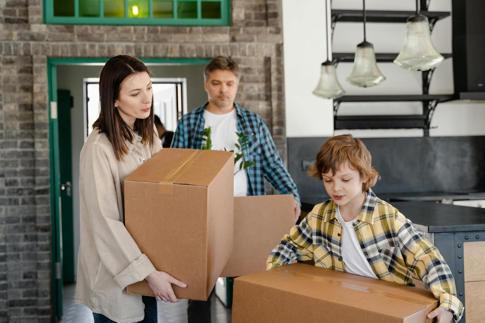 Family carrying cardboard boxes while moving into a new home, capturing a warm moment of relocation.