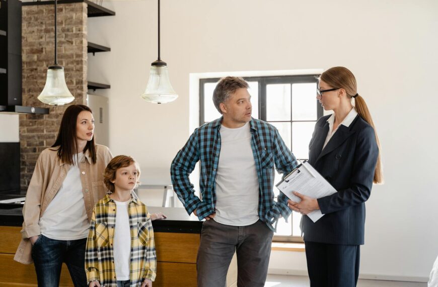 Family with child talks to real estate agent in modern kitchen during home showing.