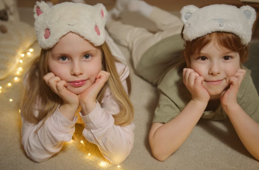 Two children lying on the floor with cute sleep masks, creating a cozy indoor atmosphere.