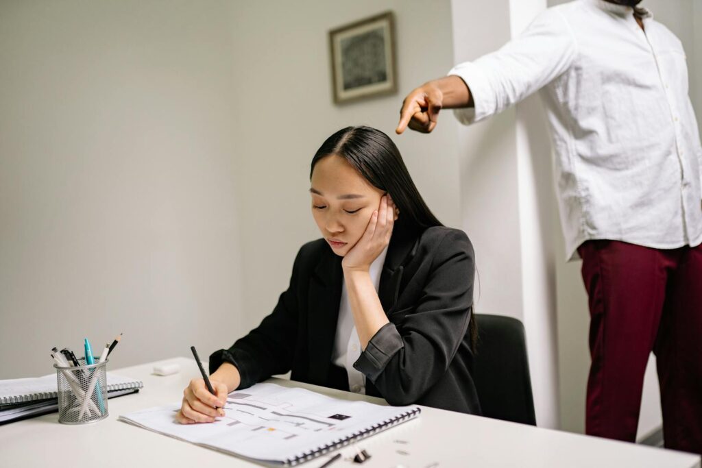 An unhappy employee experiencing workplace bullying, depicted by finger pointing in an office setting.