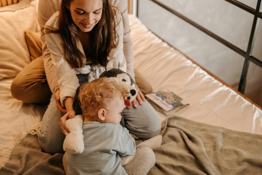 Mother and child bonding playfully on a cozy bed with a toy, capturing affection and happiness.