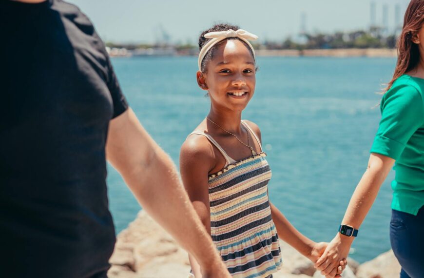 A joyful family holding hands by the ocean, enjoying quality bonding time outdoors.