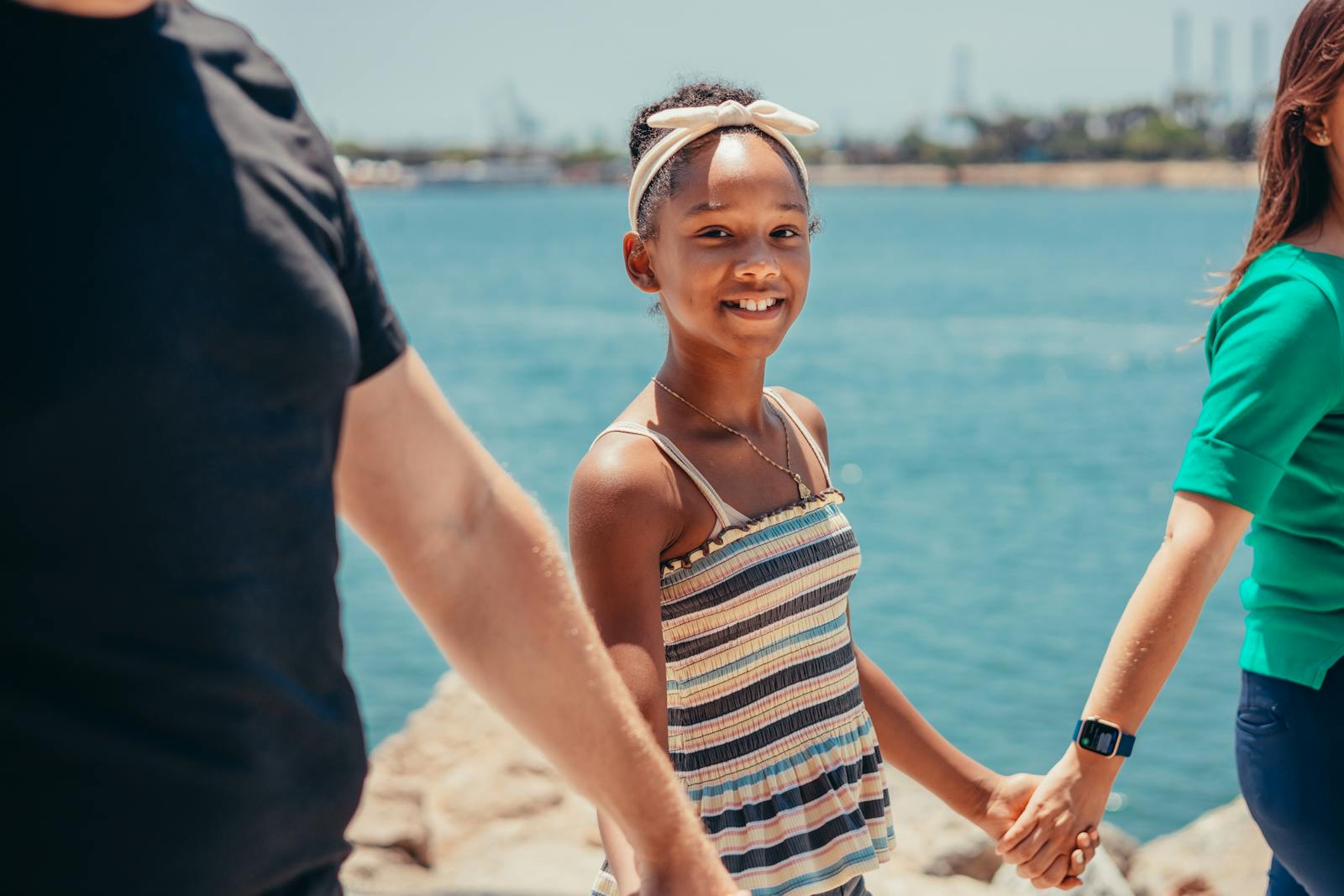 A joyful family holding hands by the ocean, enjoying quality bonding time outdoors.