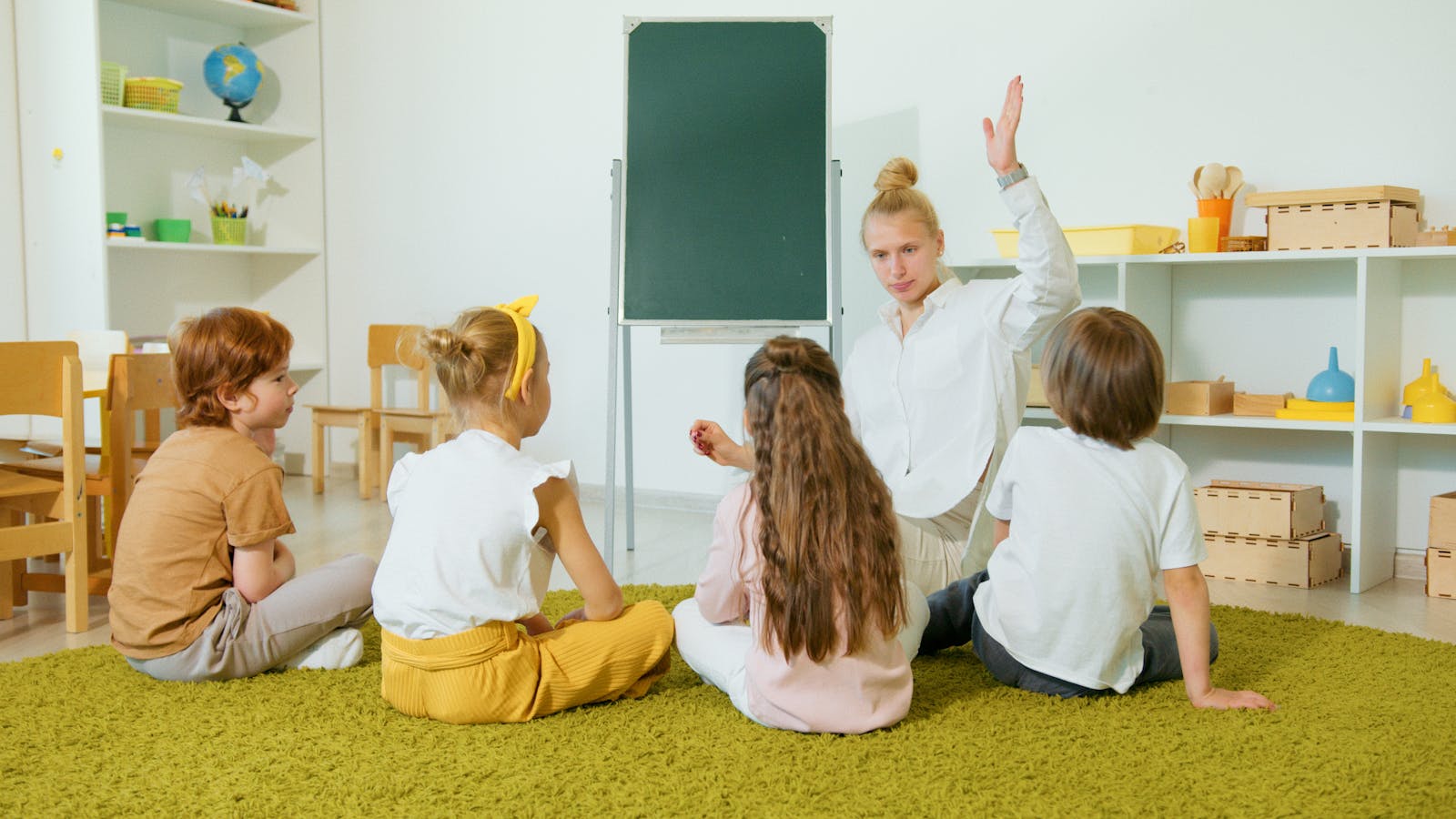 Preschool teacher interacting with children in a classroom, fostering an engaging and educational environment.