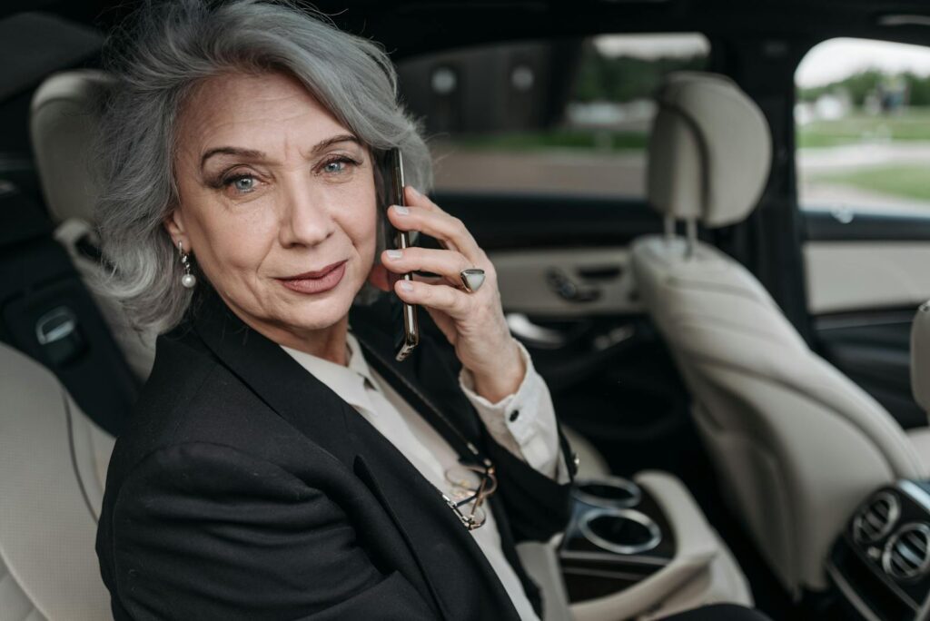 Elegant senior woman in luxury car speaking on smartphone, exuding confidence and professionalism.