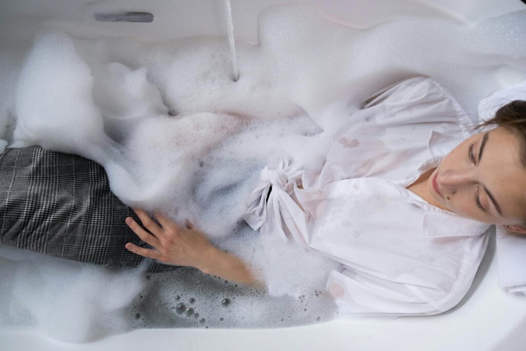 Woman in a bubble bath with white shirt for relaxation and stress relief