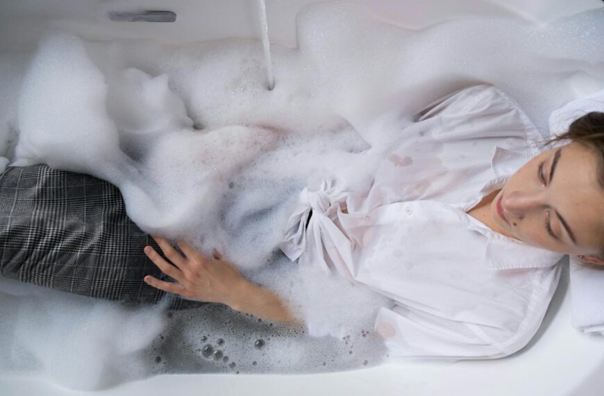 Woman in a bubble bath with white shirt for relaxation and stress relief