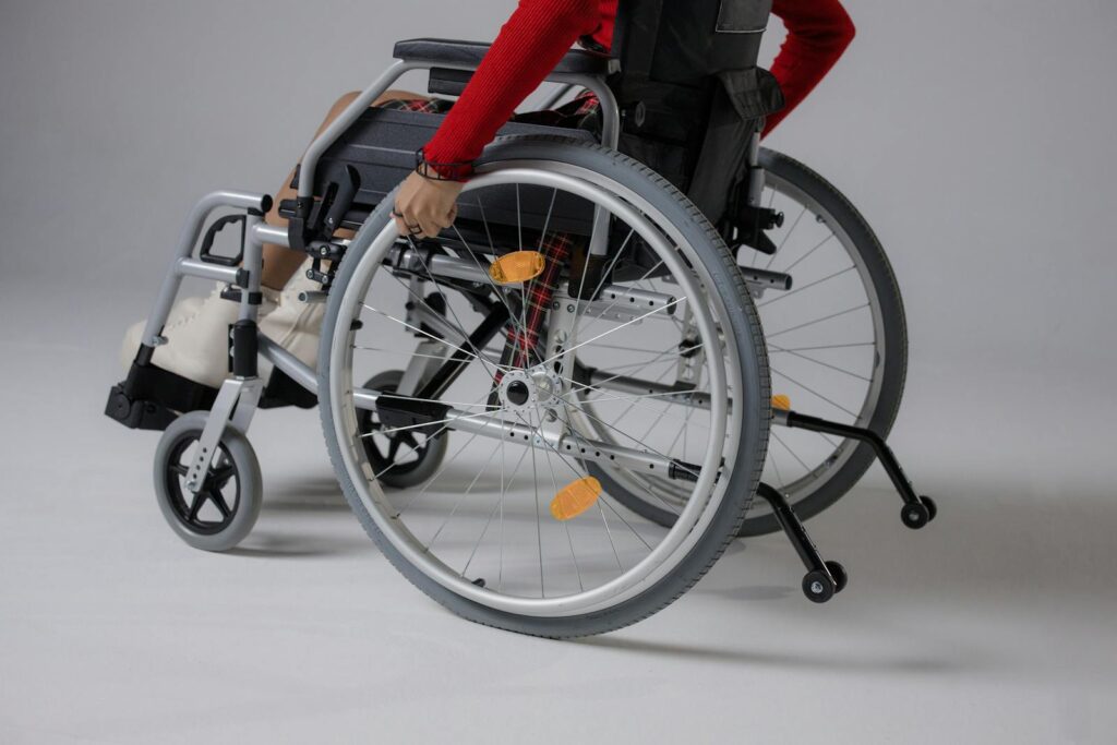 Close-up of a person using a wheelchair in a studio setting with a gray background.
