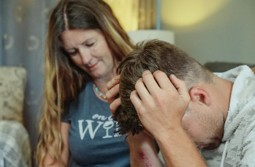 A mother provides emotional support to her stressed son indoors, conveying empathy and caring.