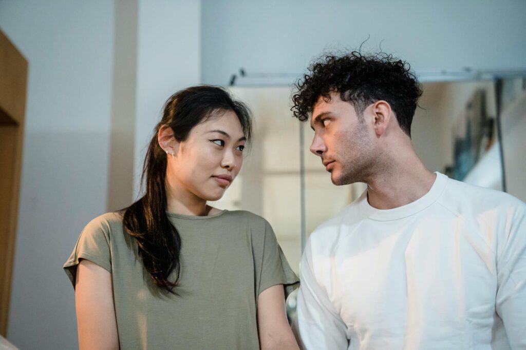 A couple looking at each other lovingly in a cozy indoor setting, highlighting a moment of connection.