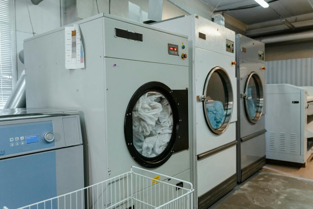Interior view of industrial laundry machines in a facility with linens being washed.