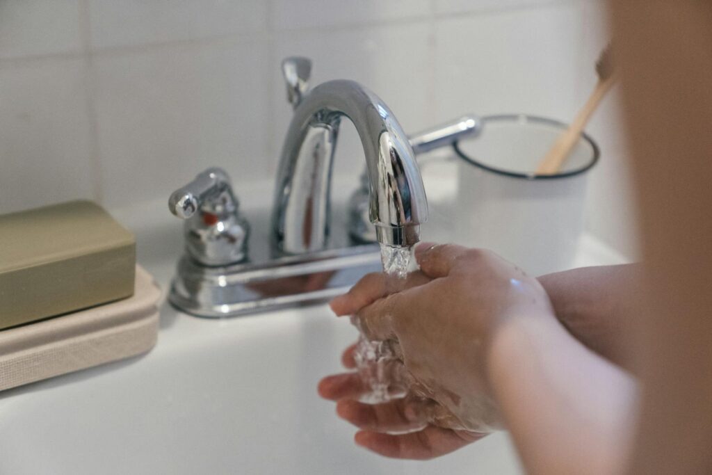 Hands washing under a faucet with running water, emphasizing hygiene and cleanliness.