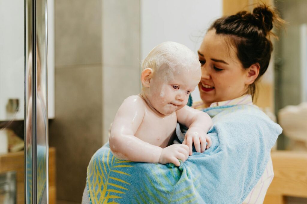 A mother lovingly holds her baby wrapped in a towel after bath time, creating a warm and tender moment.