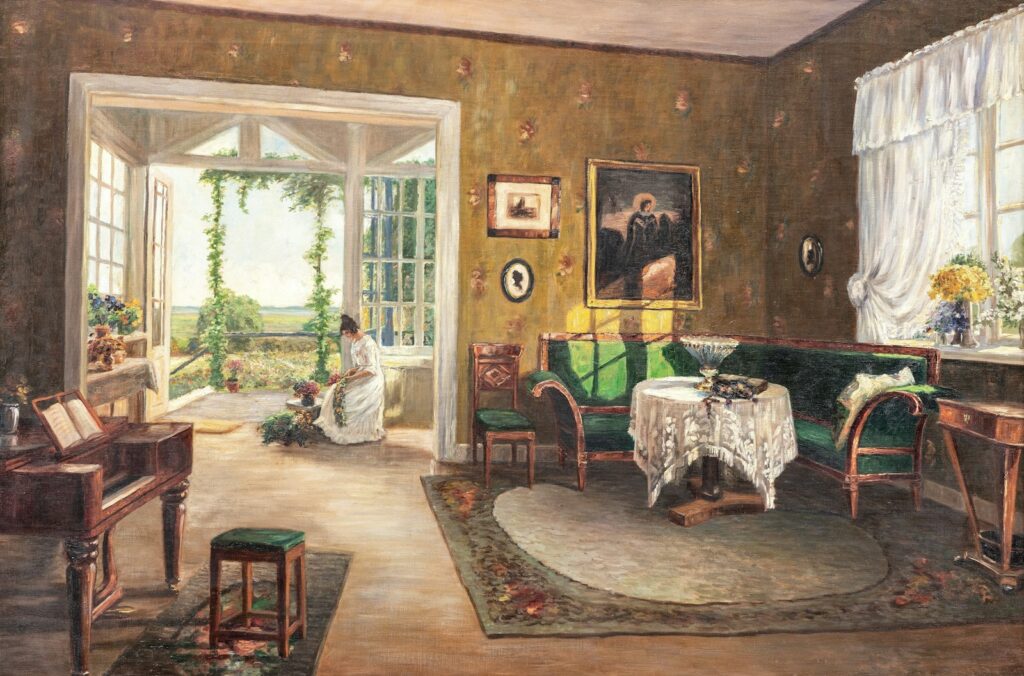 A woman sits in a sunlit conservatory overlooking a garden.