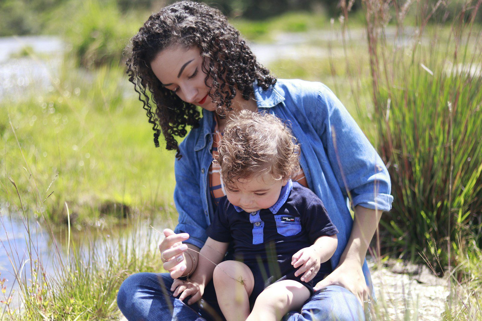 woman in blue and green hoodie carrying child in blue hoodie