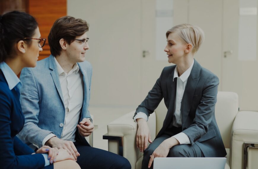 Three professionals in business attire conversing indoors.