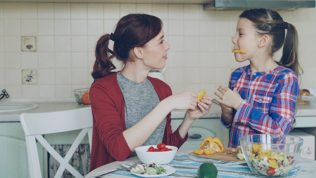Mother and daughter enjoy snacks in the kitchen.