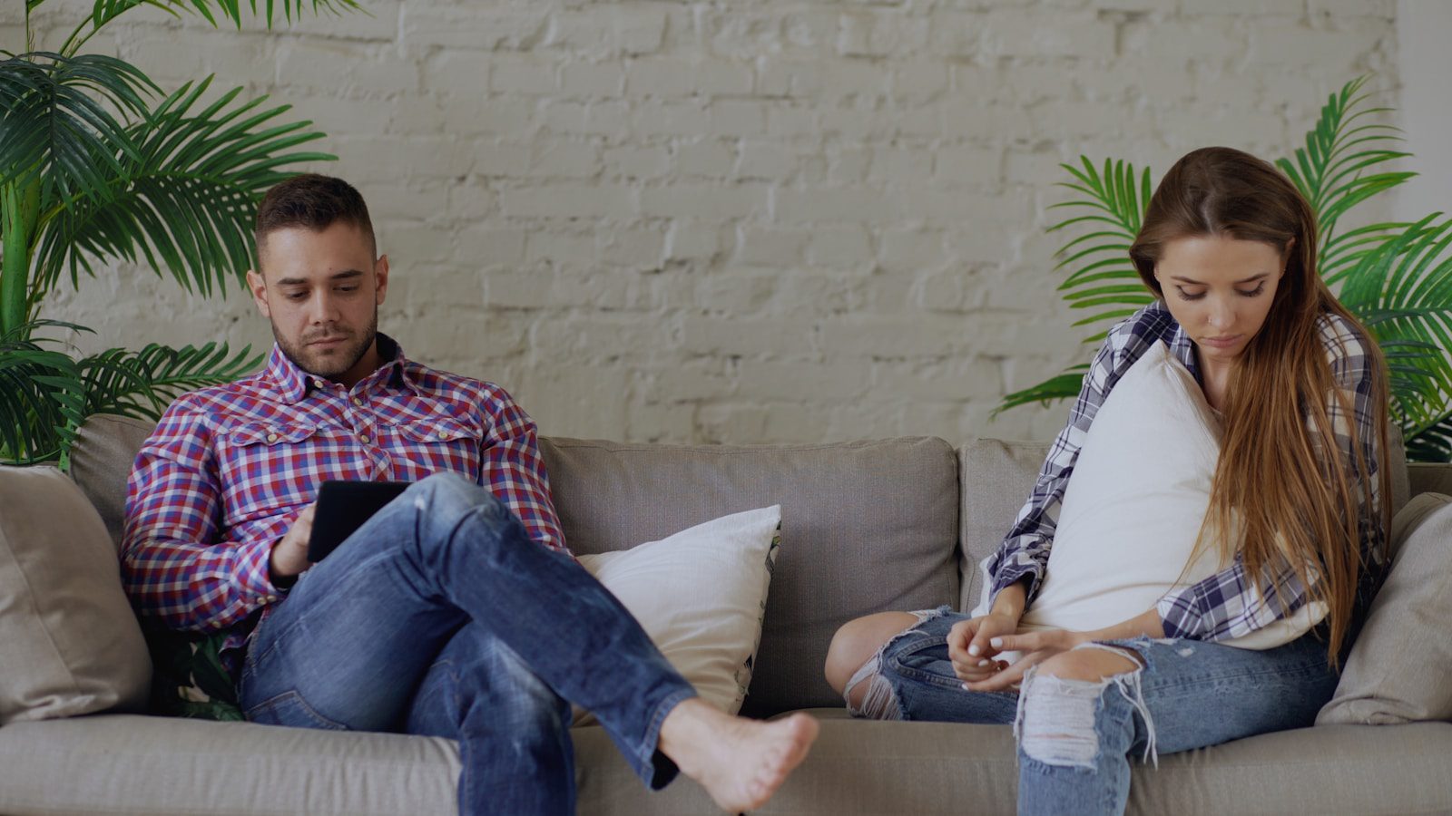 Couple sitting on sofa looking at phones