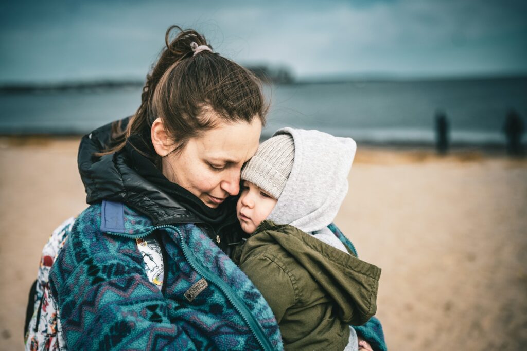 a woman holding a child on the beach