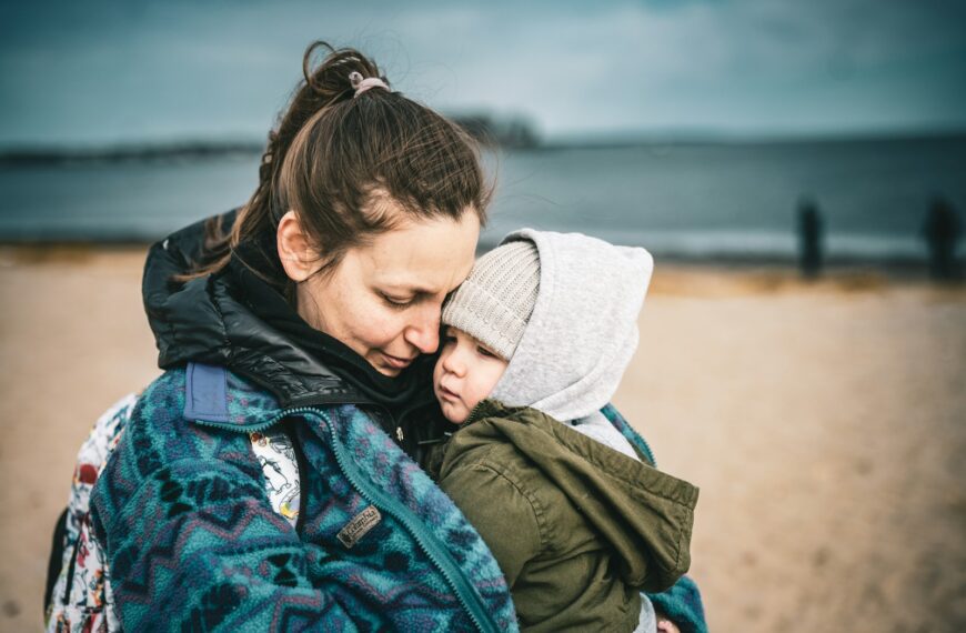 a woman holding a child on the beach
