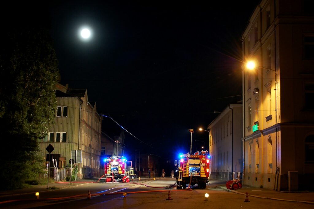Firefighters and trucks on a street at night