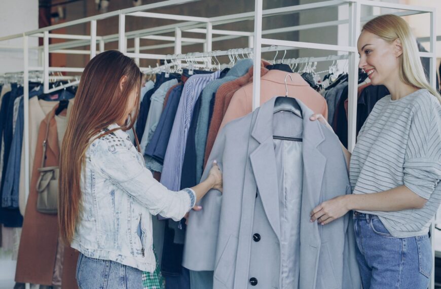 Two women browse clothing racks in a boutique.