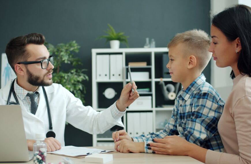Doctor examines a young boy with his mother present.