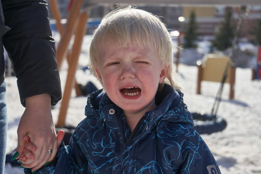 a little boy crying while holding his hand