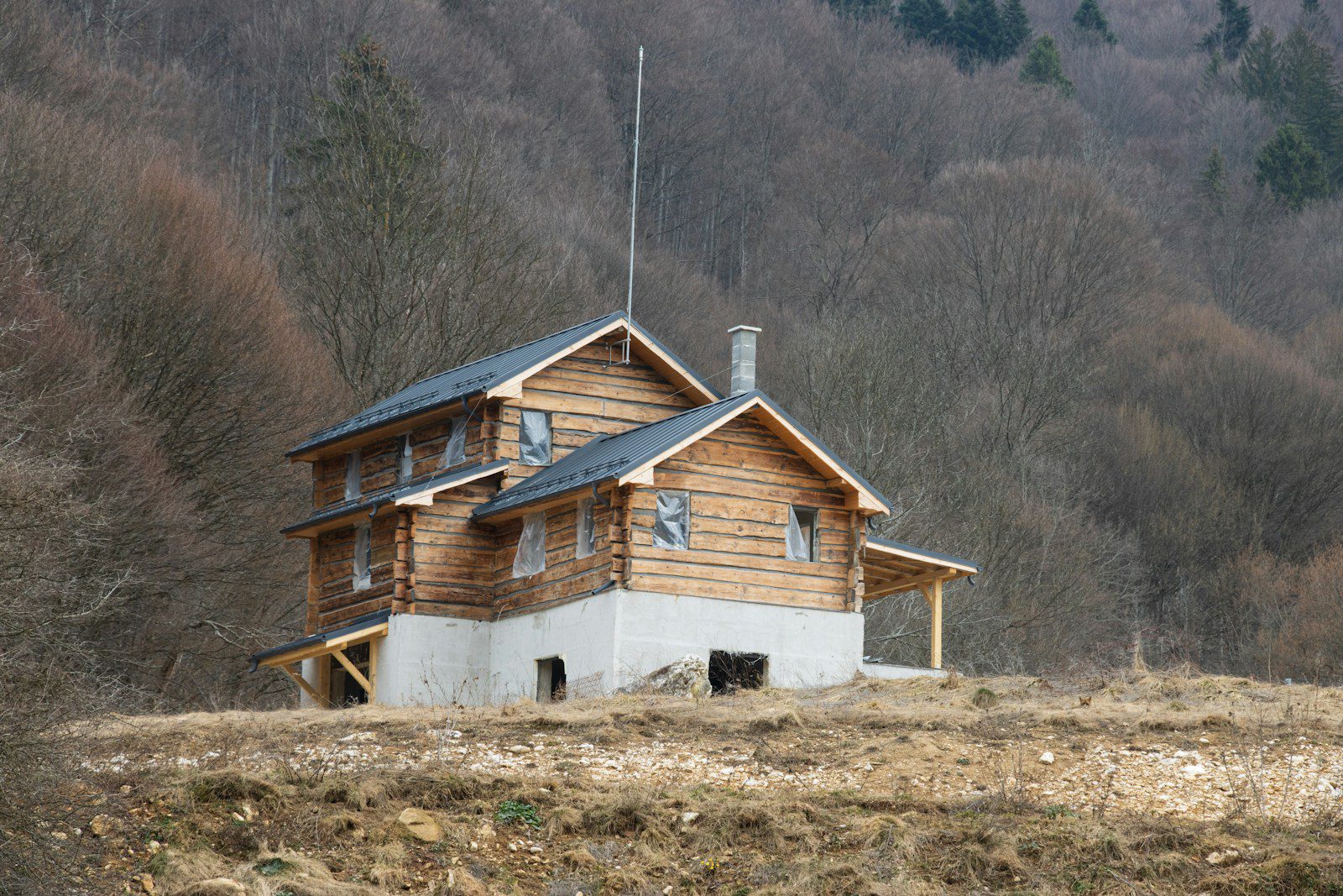 A house in the middle of a field with mountains in the background