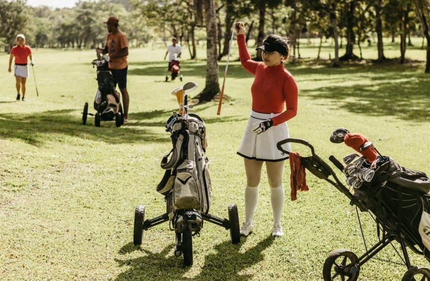 a woman in a red shirt and white skirt holding a golf club
