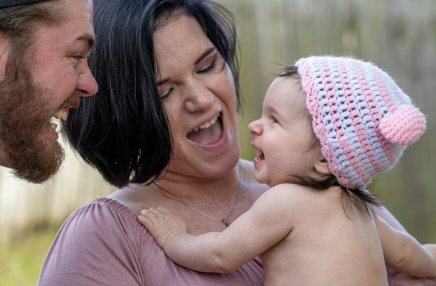 woman in pink knit cap carrying baby in pink knit cap