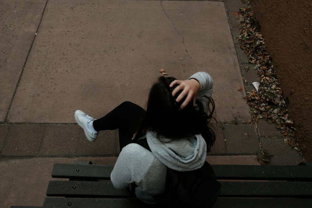 a person sitting on a bench on a sidewalk
