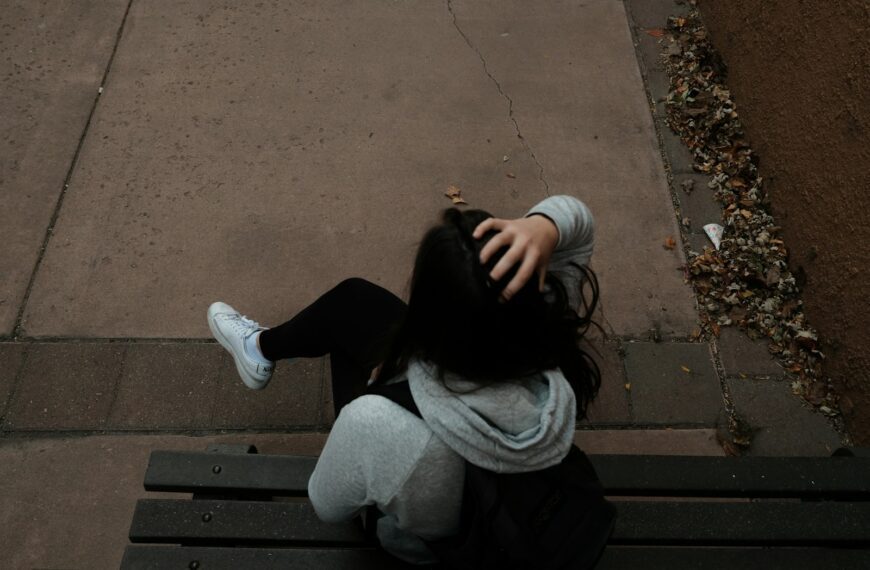a person sitting on a bench on a sidewalk