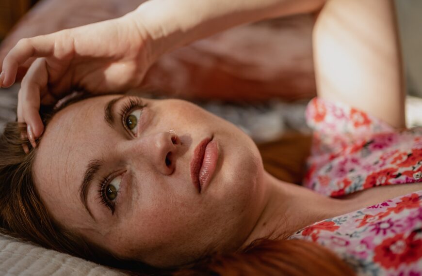 a close up of a woman lying down and looking at the camera